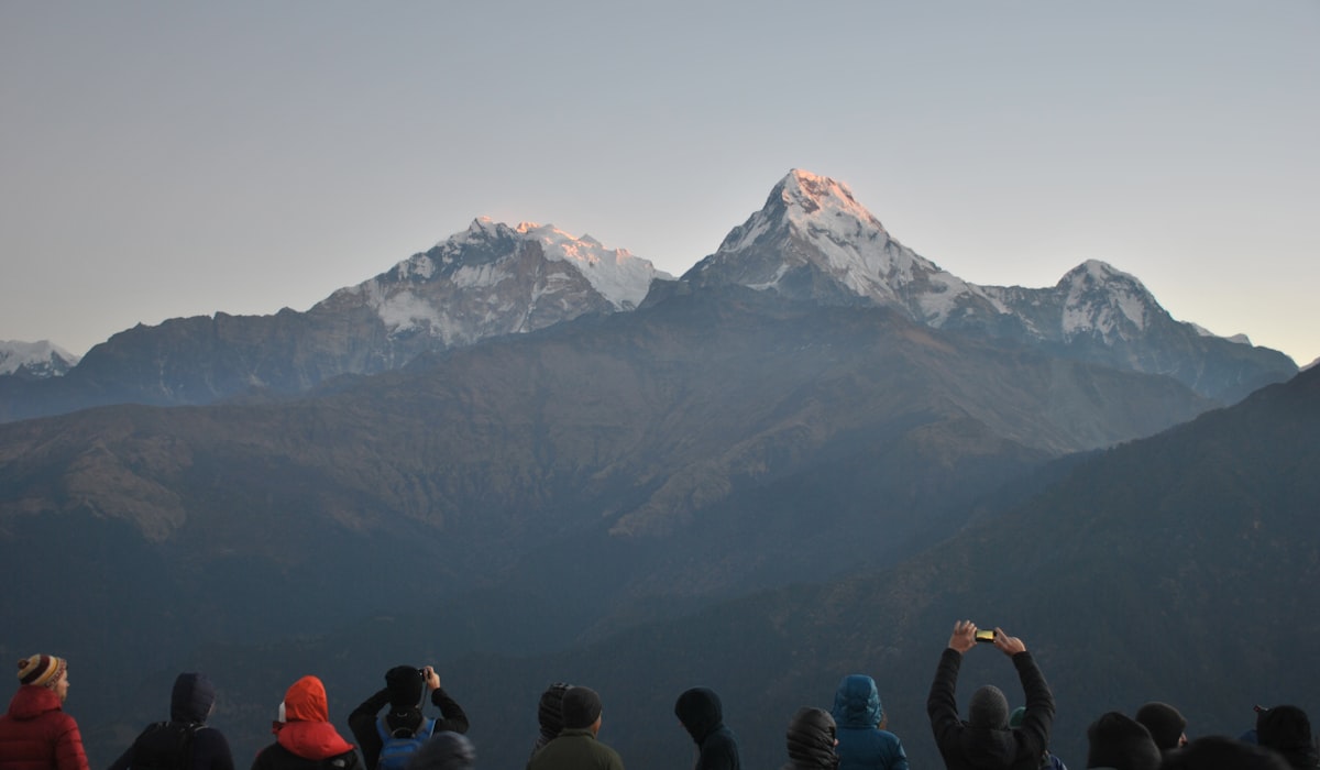 Trekkers watching sunrise light hit Annapurna South from the Poon Hill viewpoint above Ghorepani